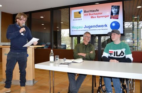 Christian Otto, Gymnasiallehrer an der Wilhelm-Bläsig-Schule (stehend), stellt den jungen Buchautor Max Sprenger vor.  Schulleiter Rüdiger Becker (sitzend) liest ausgewählte Passagen aus dem Buch vor. Bilder: Jagode